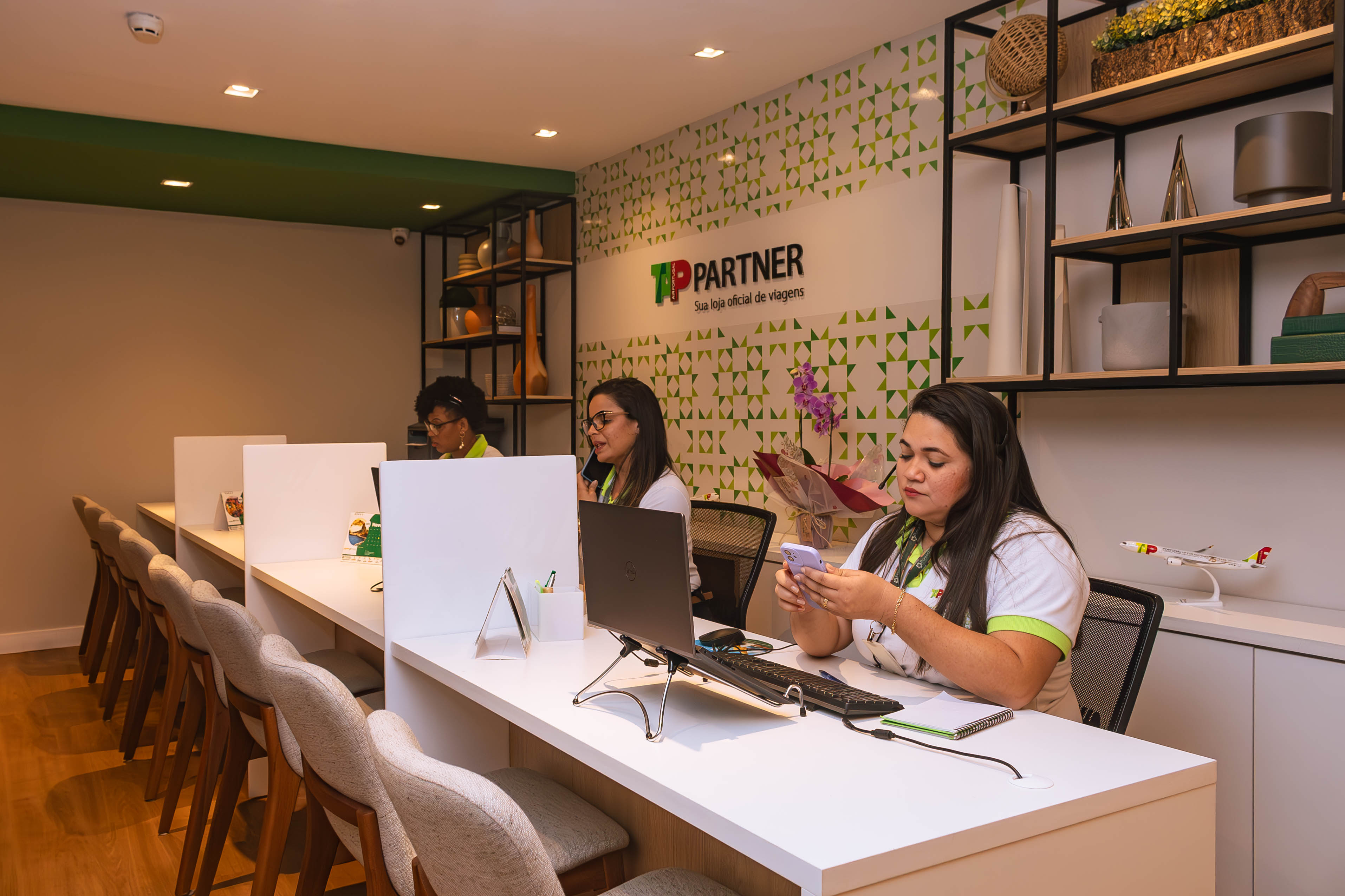 Atendentes trabalhando na Sala TAP Partner com miniaturas de avião TAP